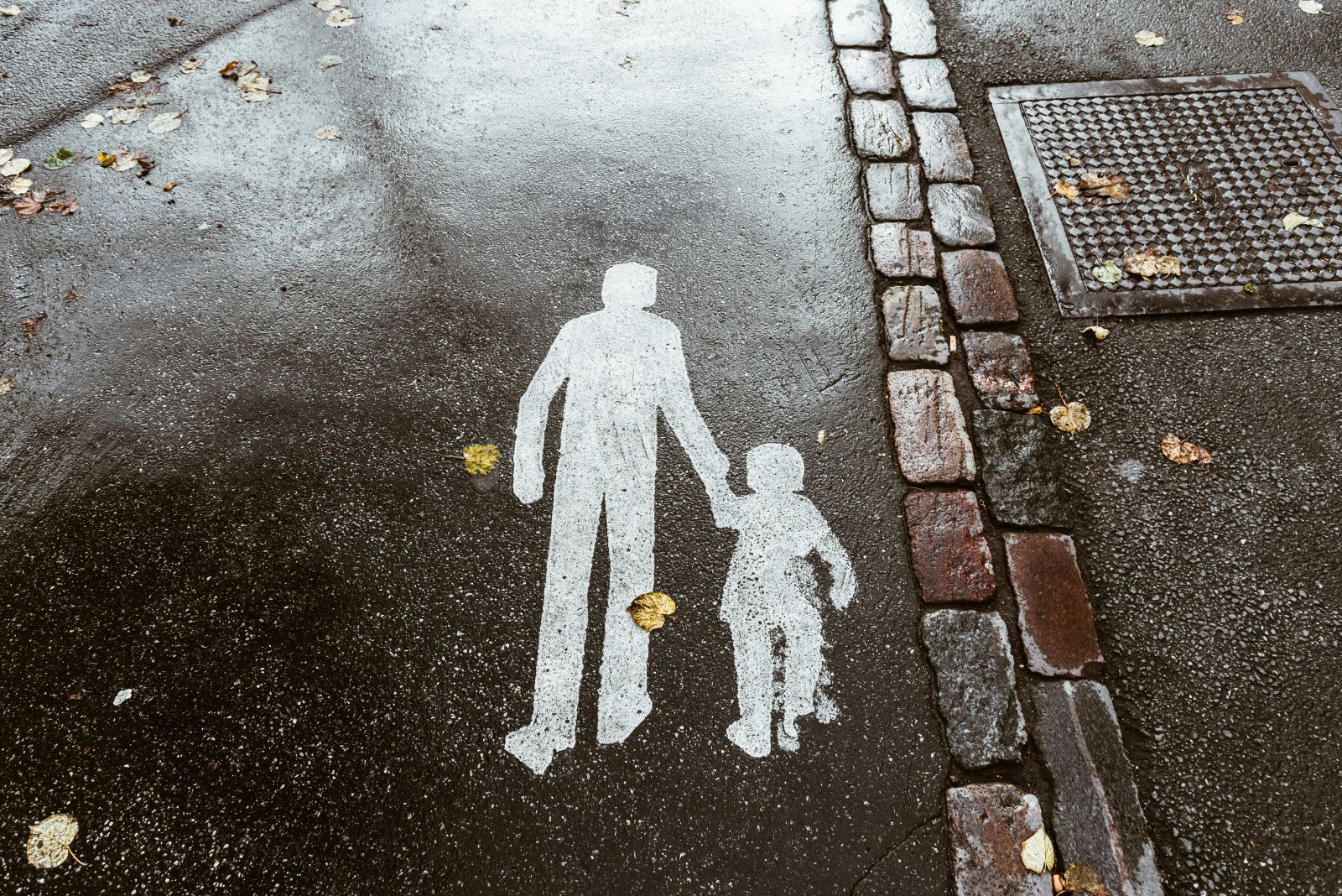 Sidewalk painting of silhouetted man holding the hand of a child.